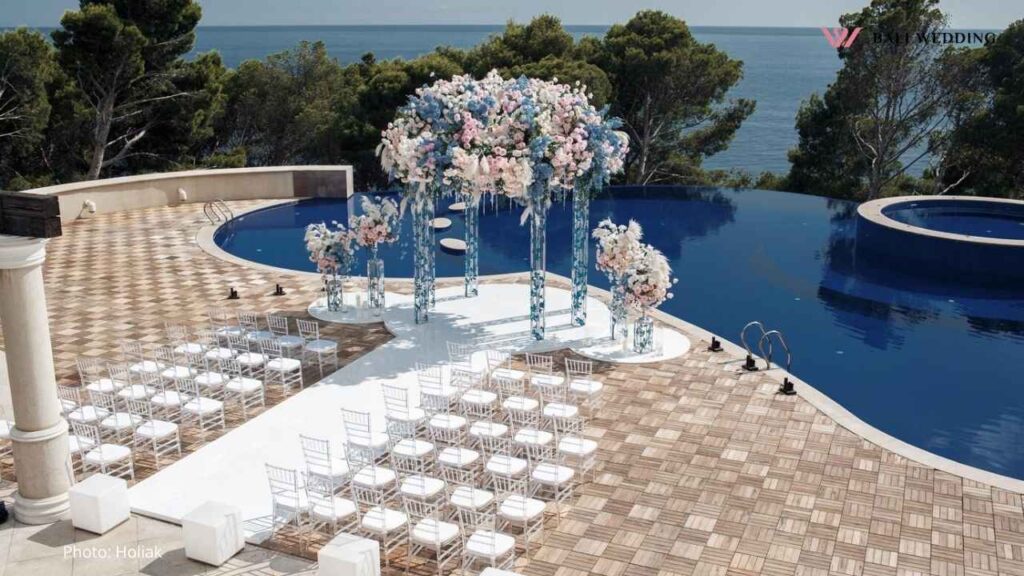 Wedding setup by pool with ocean view and elegant floral decorations