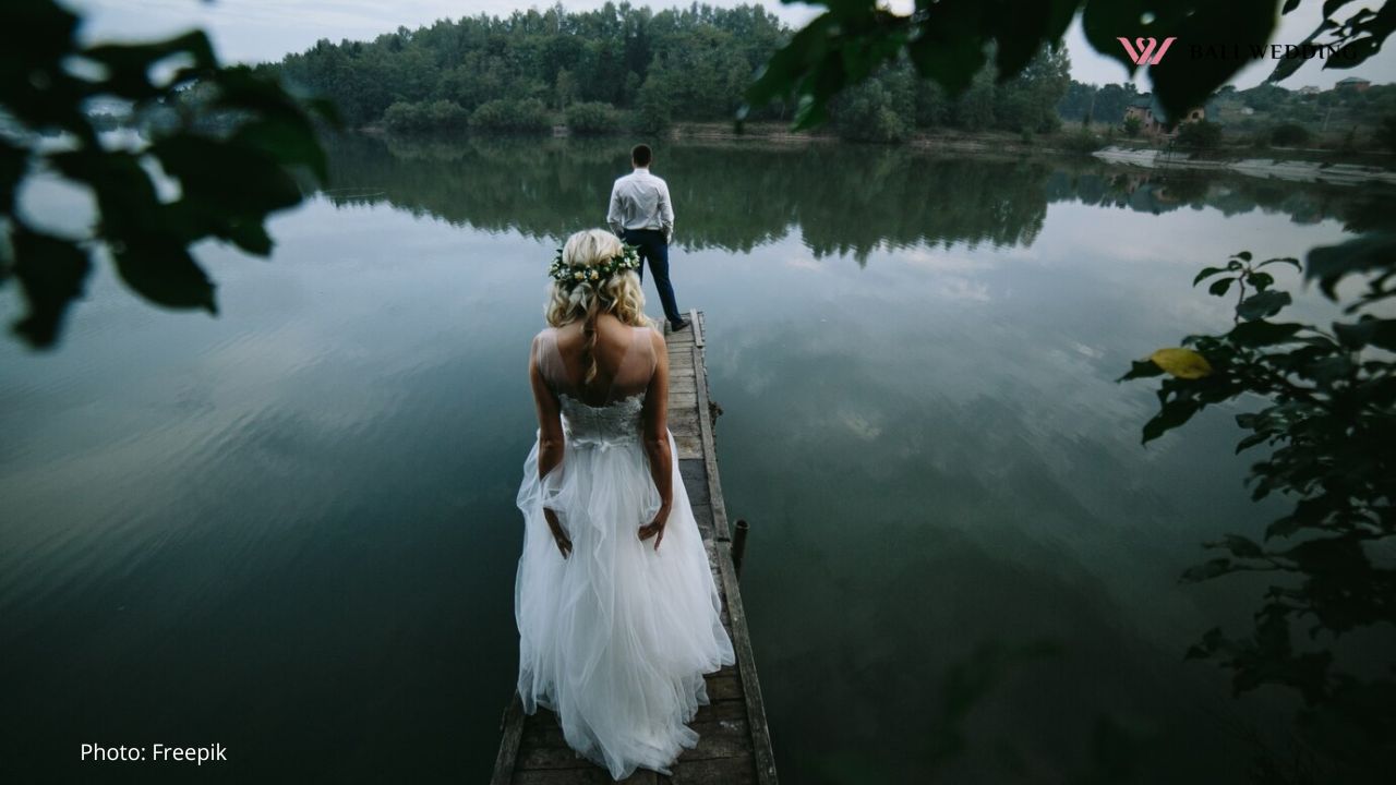 Bride with her husband in front looking at a lake