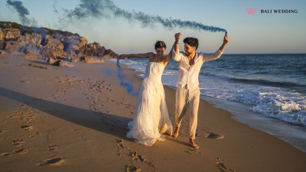 Picture of a beautiful couple posing with a blue smoke bomb in the beach