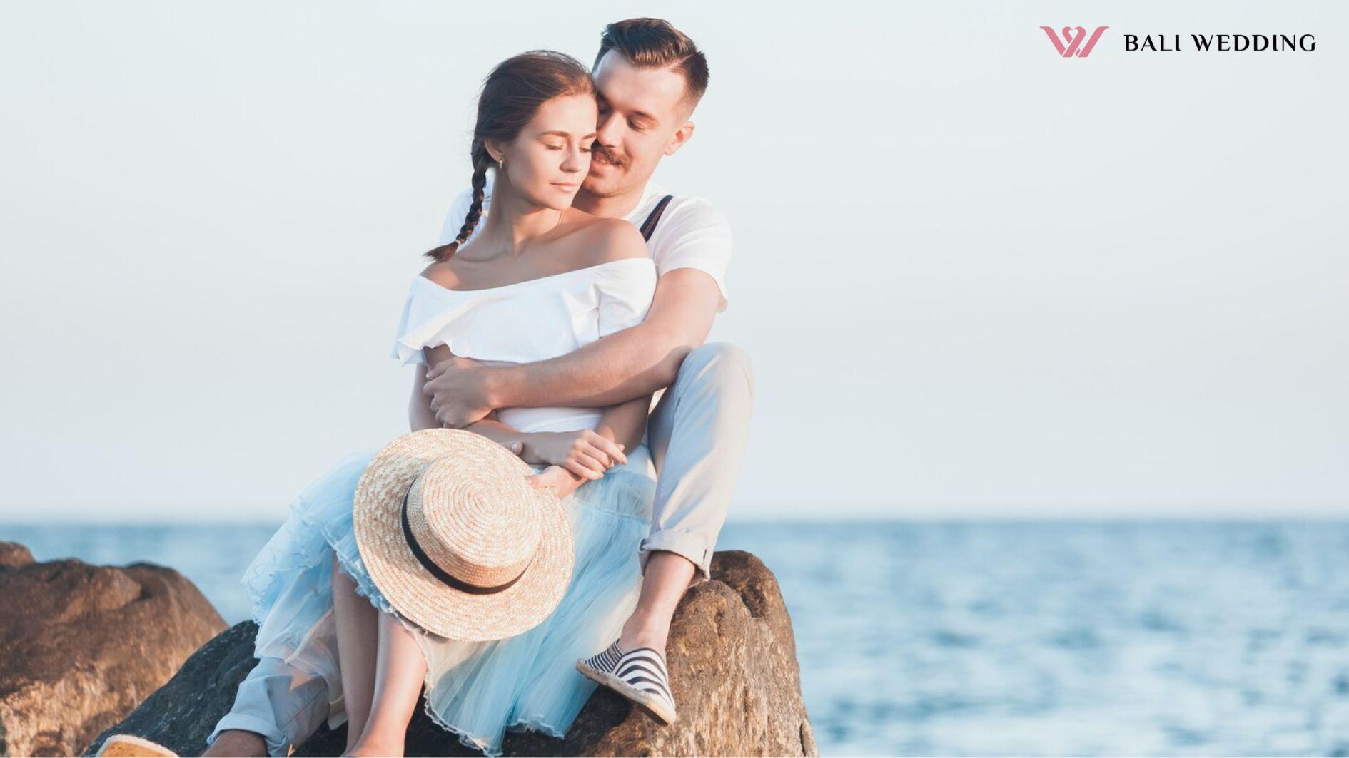 Happy young romantic couple relaxing on the beach and watching the sunset