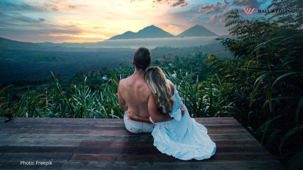 Rear view of couple sitting on mountain against sky