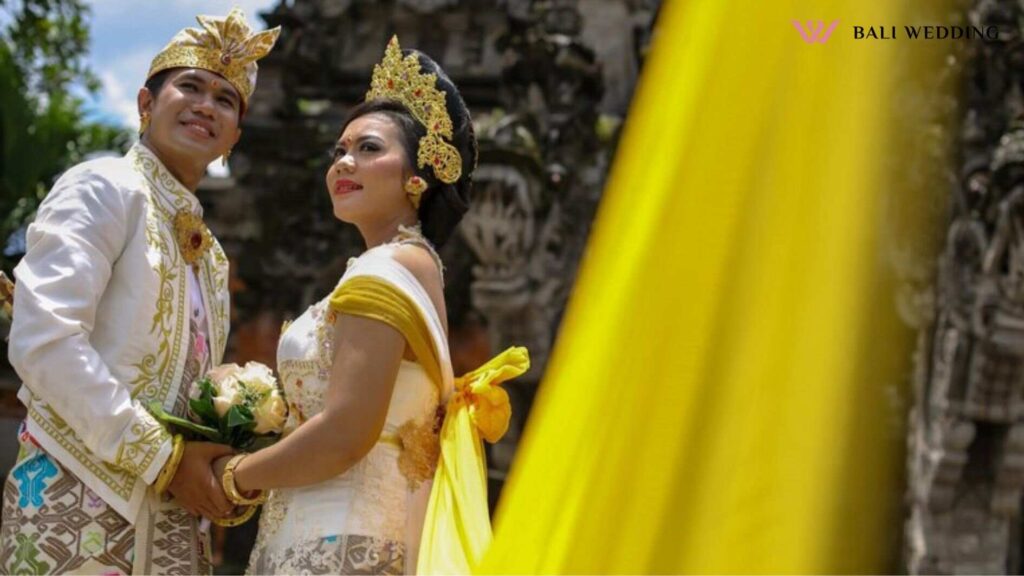 The bride and groom dressed in balinese traditional clothes stand in front of the temple