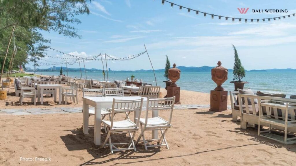 White chairs and table on beach with a view of blue ocean and clear sky